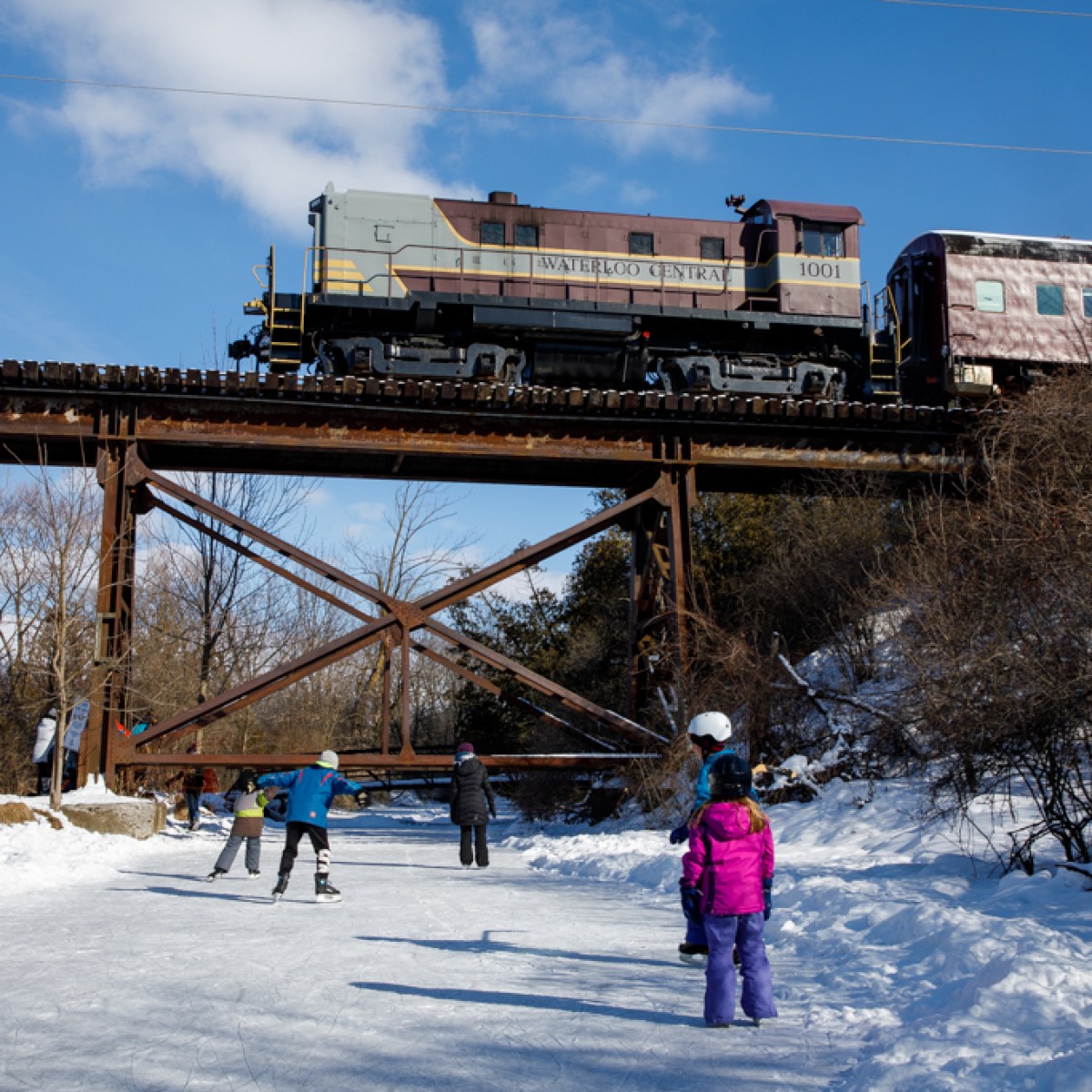 a group of people riding skis on top of a snow covered bridge