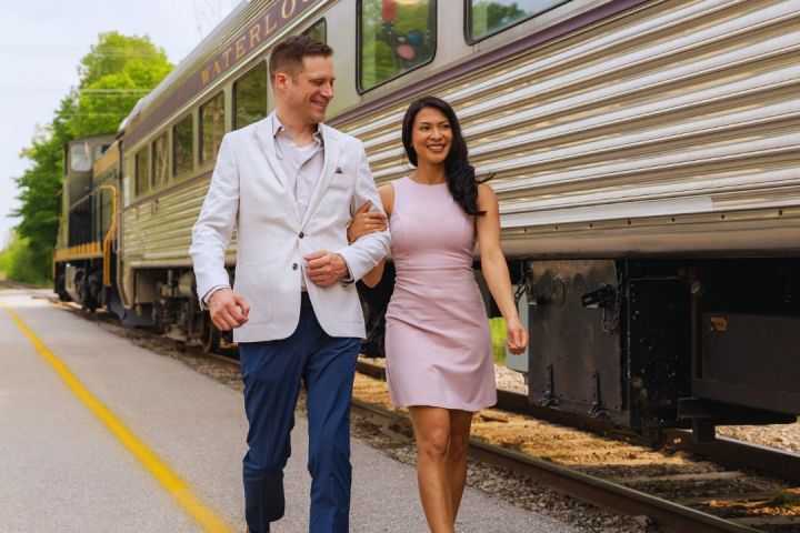 Couple walking on train platform beside a vintage train.