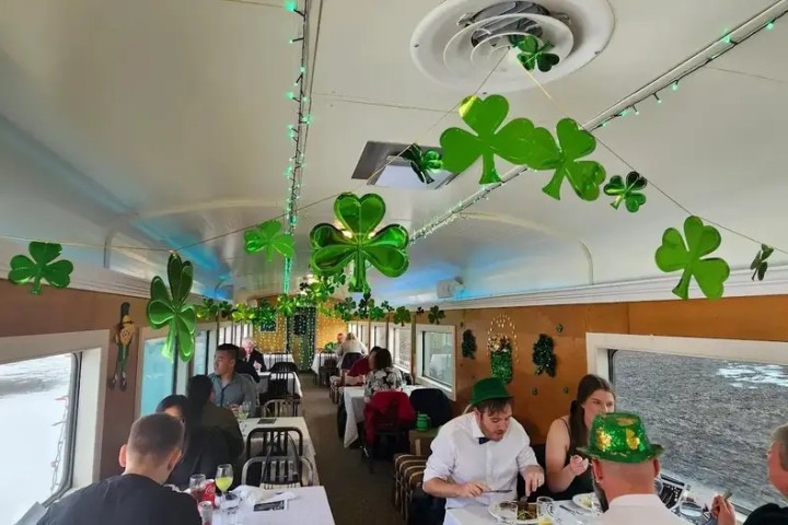 People dining in a train car decorated with green shamrocks for St. Patrick's Day.