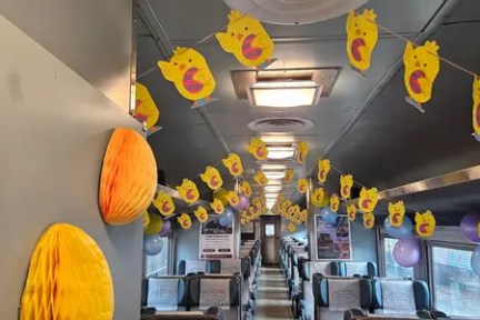 Train car decorated with yellow chick banners and balloons.