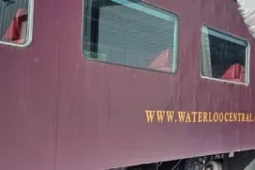 Person in rabbit costume in front of a maroon train with 'waterloocentral.ca' on its side.