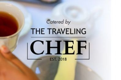 Hand holding a teacup with 'Catered by The Traveling Chef Est. 2018' text overlaid.