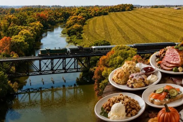 Train on bridge over river with plates of food in foreground, surrounded by autumn trees and fields.