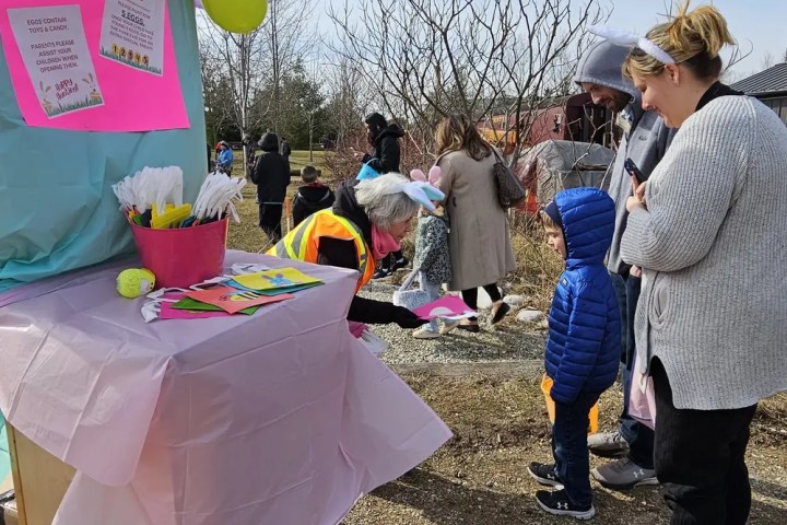 Outdoor event with people at a decorated table with balloons and welcome sign.