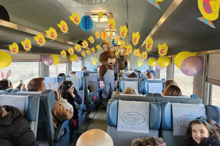Train interior decorated for Easter with balloons, chick garlands, and people in costume.