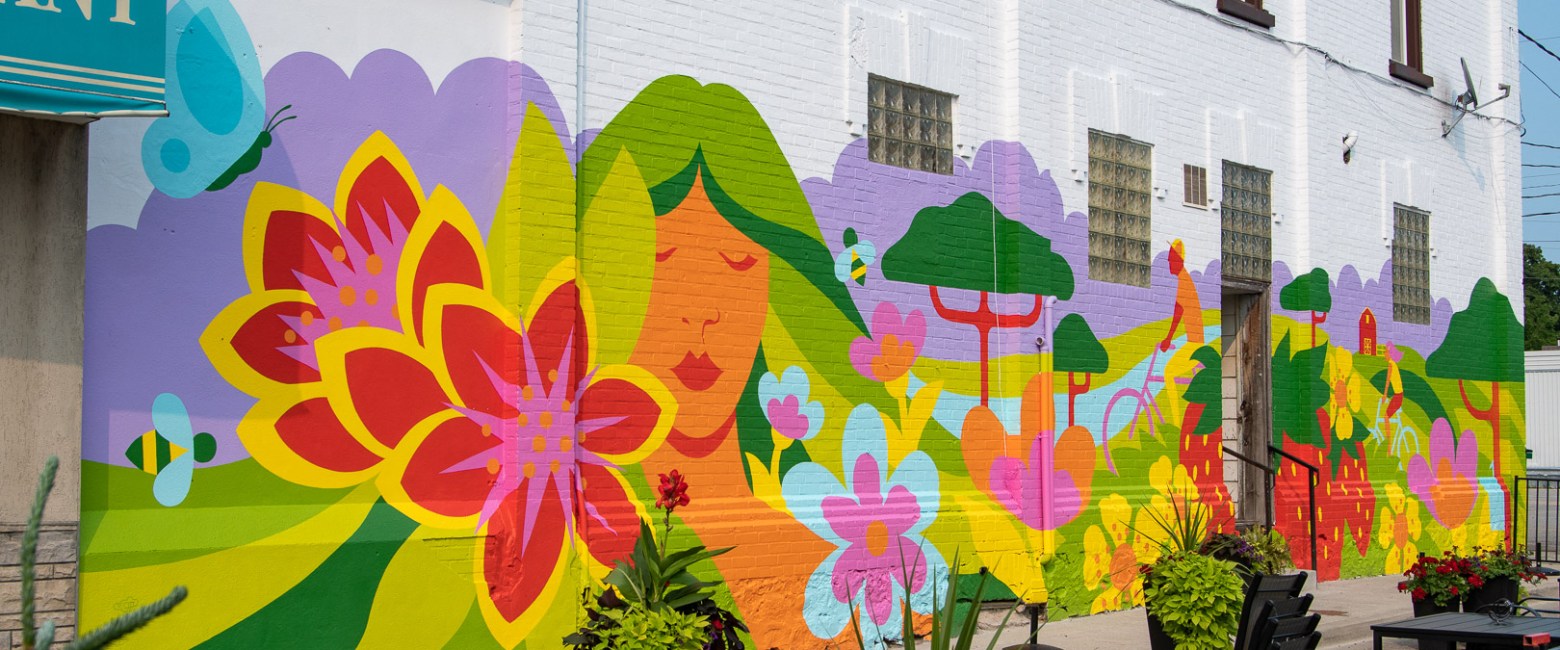 Vibrant mural of colorful flowers and female figure on a building wall.