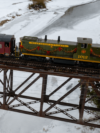 Train on snow-covered bridge with red passenger cars.