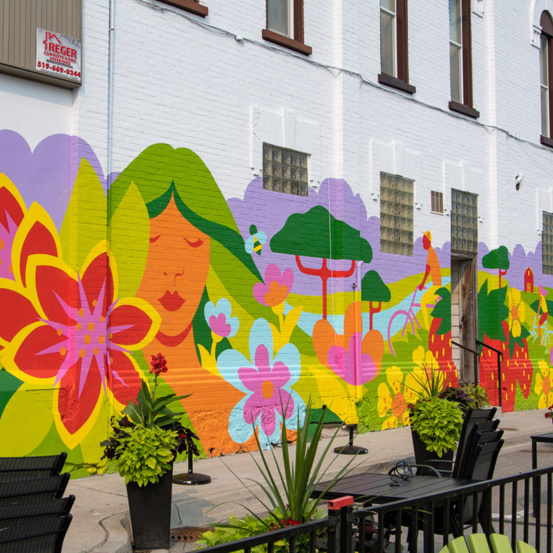 Colorful mural of flowers and abstract shapes on a building wall.