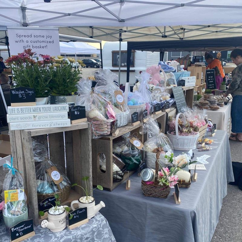 Market stall with gift baskets, flowers, and decorative items on display.