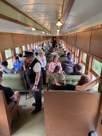 Passengers seated in a vintage train car with wood paneling.