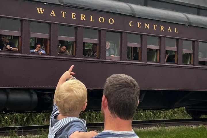 Man holds child pointing at passing Waterloo Central train.